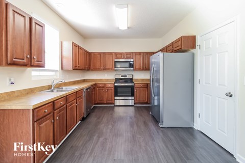 A kitchen with wooden cabinets and a grey refrigerator.