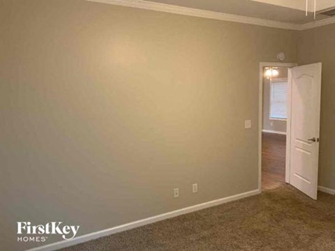 an empty living room with a white door and a window