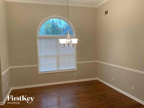 an empty dining room with a window and a chandelier