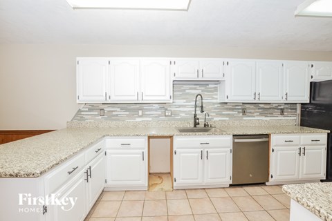A kitchen with white cabinets and a granite countertop.