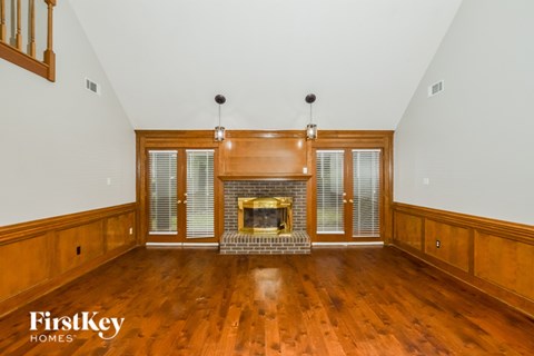A spacious living room with wood floors and a fireplace.