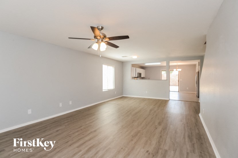 an empty living room with a ceiling fan and wood flooring