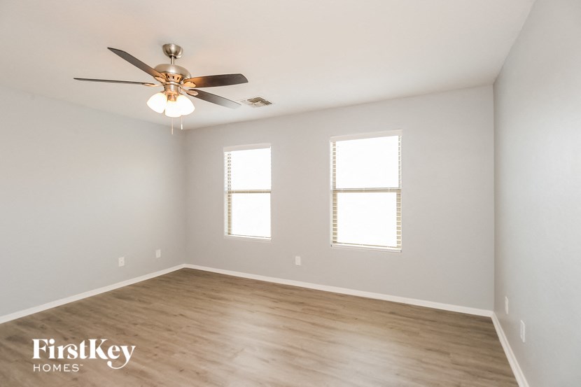 an empty room with a ceiling fan and two windows