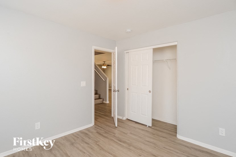 a bedroom with a door to a closet and a hallway with a staircase