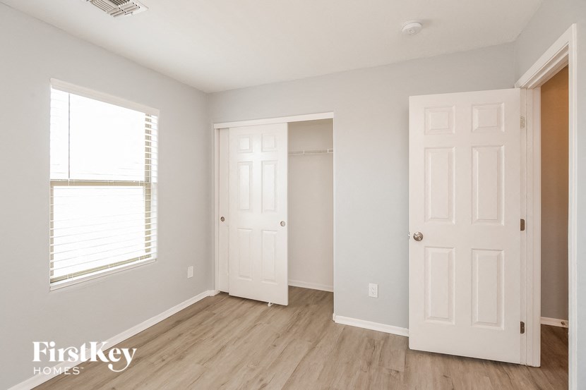 a bedroom with two closets and a window and a wooden floor