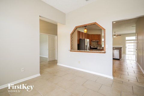A spacious room with a mirror reflecting a kitchen.