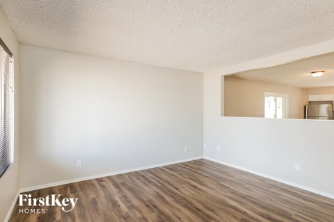 the spacious living room with wood flooring and white walls
