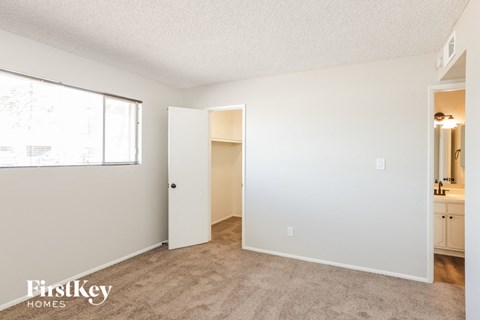 a bedroom with a large window and a door to a bathroom