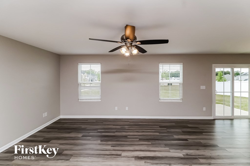 A spacious room with a ceiling fan and wooden flooring.