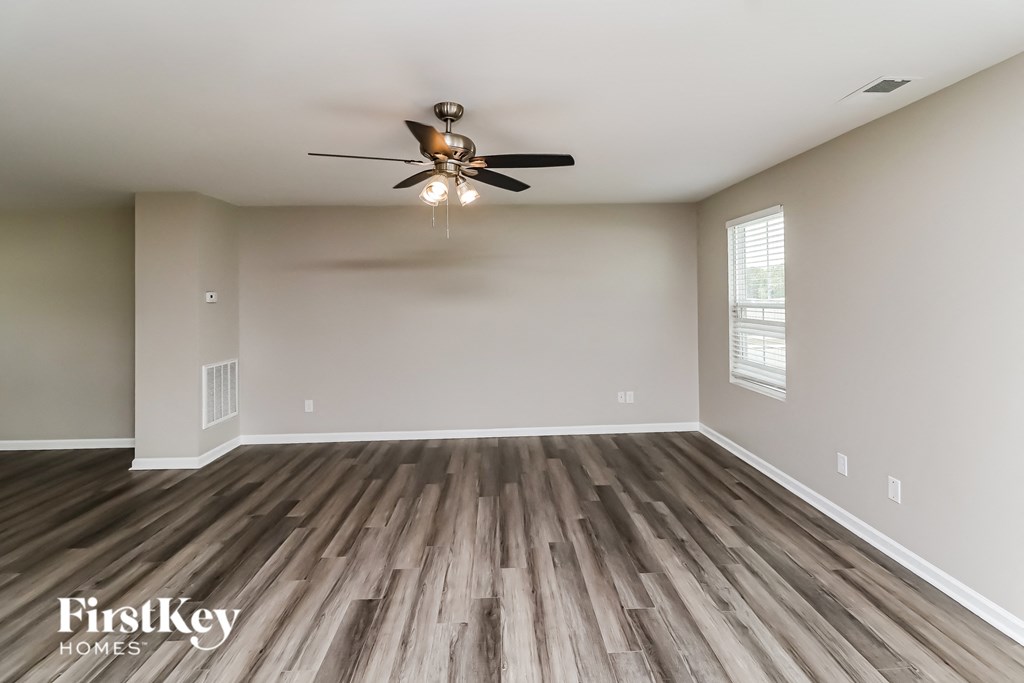 A spacious room with wooden flooring and a ceiling fan.