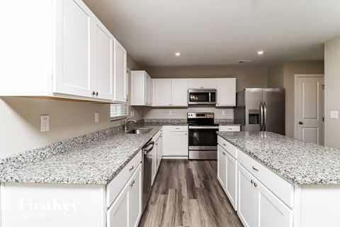 A kitchen with white cabinets and granite countertops.