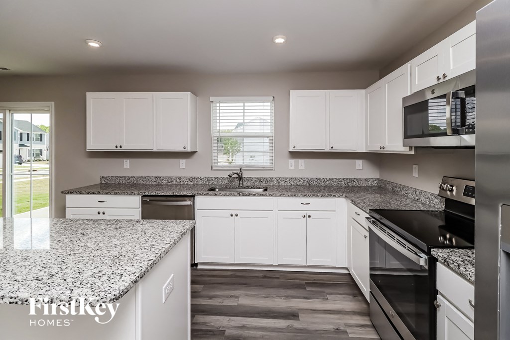 A kitchen with white cabinets and a granite countertop.
