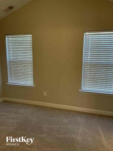 a living room with two windows and a carpet