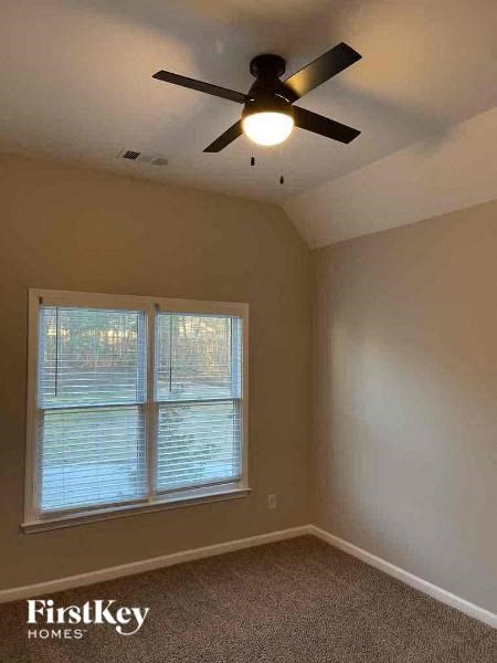 an empty bedroom with a ceiling fan and a window