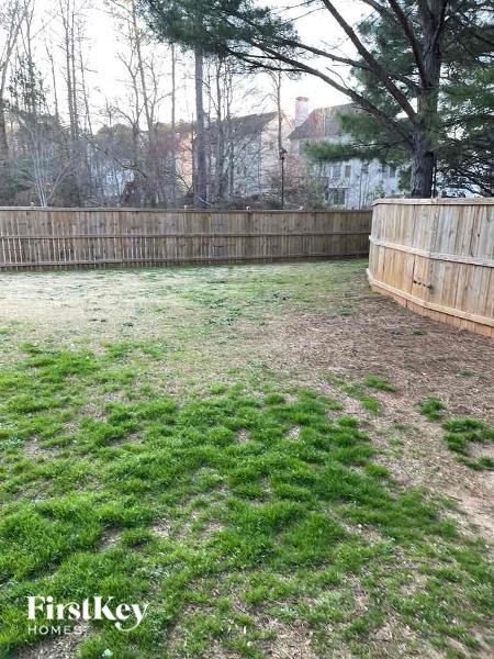 a backyard with a wooden fence and green grass