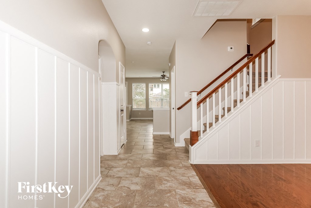 A spacious hallway with a staircase and a skylight.