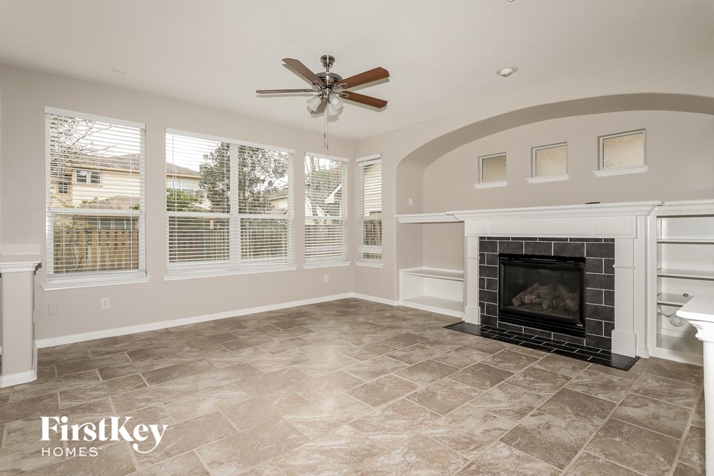 A living room with a fireplace and a ceiling fan.