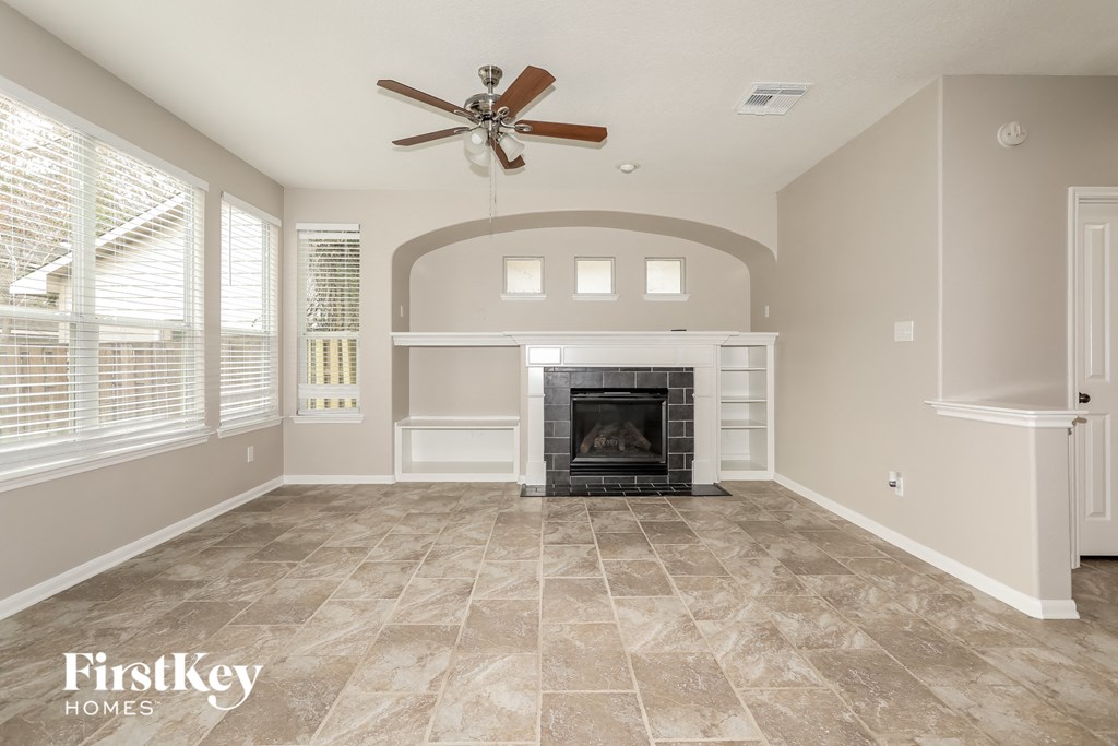 A spacious living room with a fireplace and a ceiling fan.