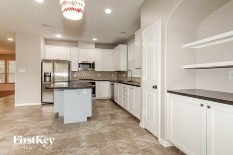 A kitchen with white cabinets and a refrigerator.