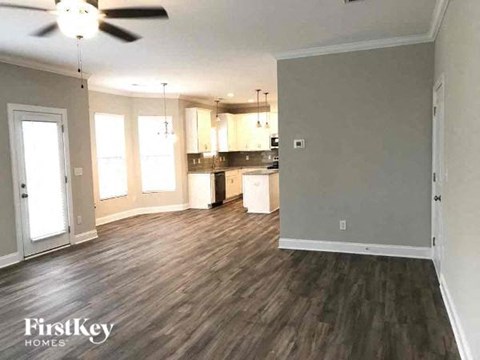 A spacious room with wood flooring and a ceiling fan.