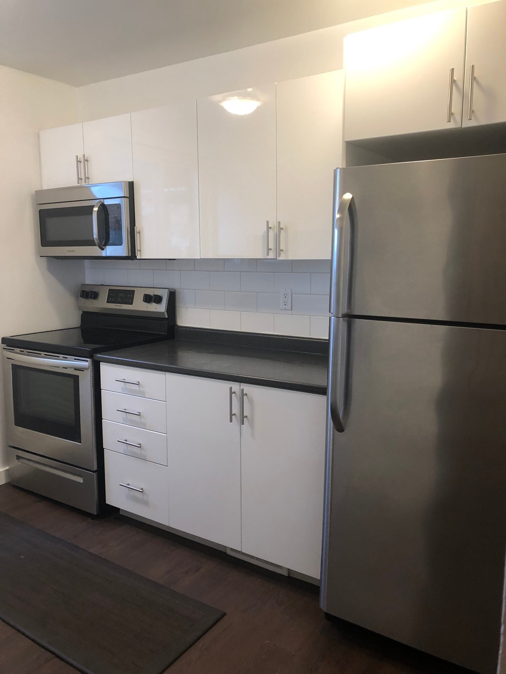 a kitchen with white cabinets and a stainless steel refrigerator