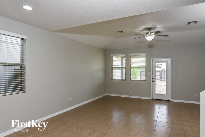 A spacious room with a ceiling fan and a door leading to a balcony.