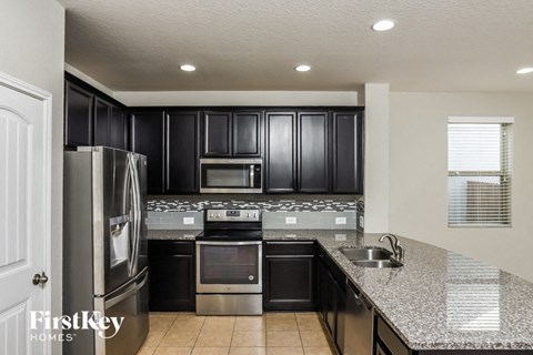 A kitchen with black cabinets and stainless steel appliances.
