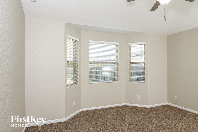 A room with a carpet floor and a ceiling fan.