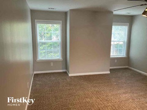 a empty room with a carpeted floor and two windows