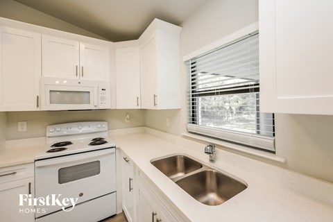 a white kitchen with white cabinets and white appliances and a window