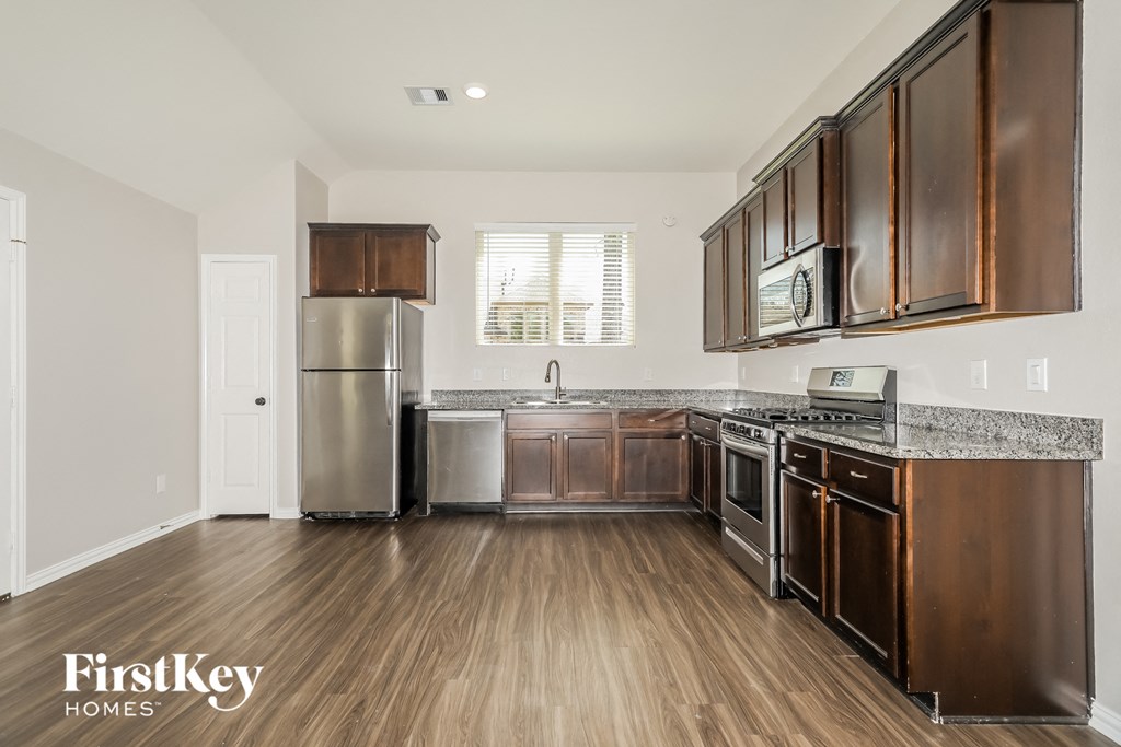a kitchen with wood flooring and stainless steel appliances and wooden cabinets