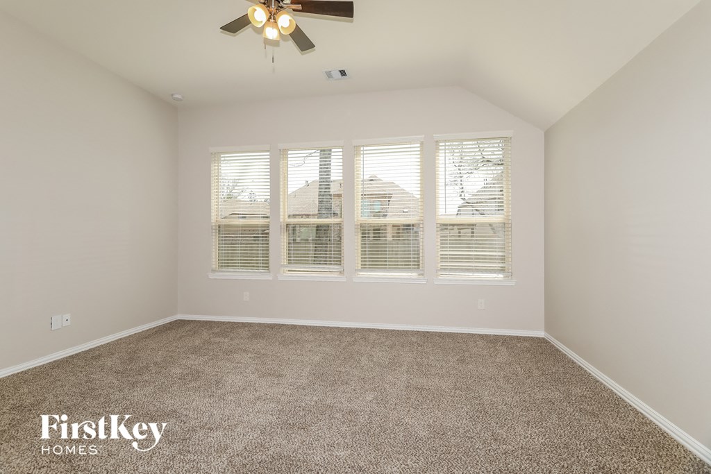the master bedroom has a large window and carpeted flooring