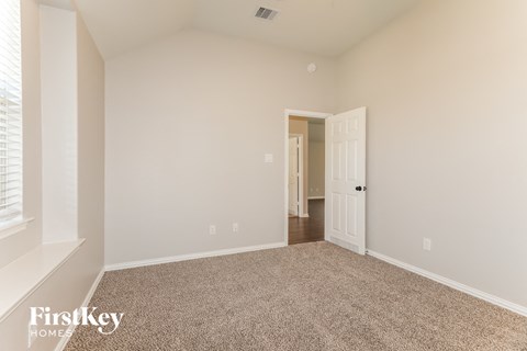 a spacious living room with carpet and a door to a hallway