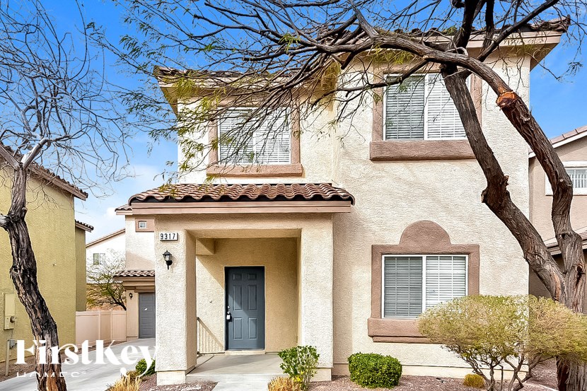 A house with a blue door and a tree in front of it.