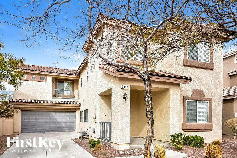 A beige house with a tree in front of it.