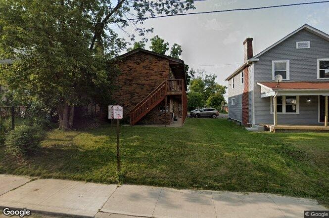 a house on the side of a street next to a yard