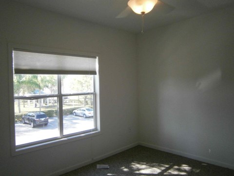 a bedroom with a large window and a lamp on the ceiling