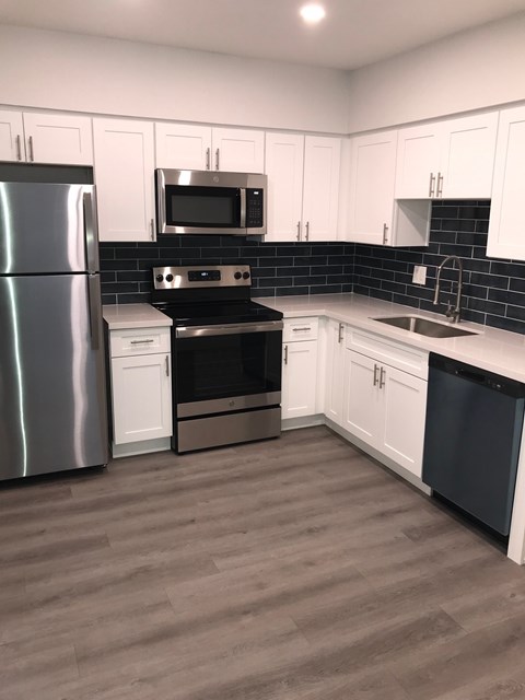 A kitchen with white cabinets and a black stove top oven.