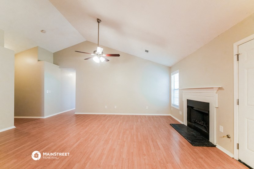 an empty living room with a fireplace and a ceiling fan