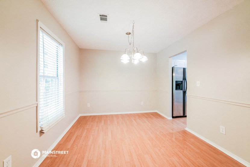 the spacious living room with wood flooring and white walls