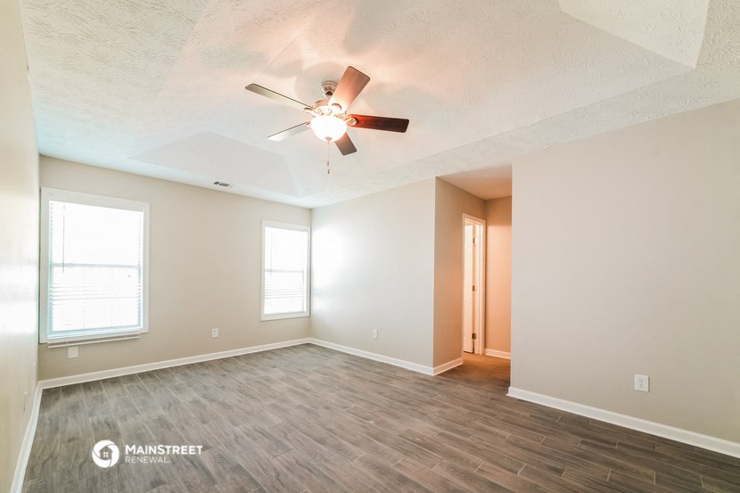 the spacious living room with ceiling fan and wood flooring