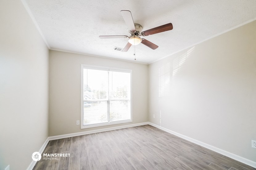an empty room with a ceiling fan and a window