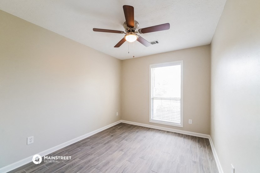 the spacious living room with wood flooring and a ceiling fan
