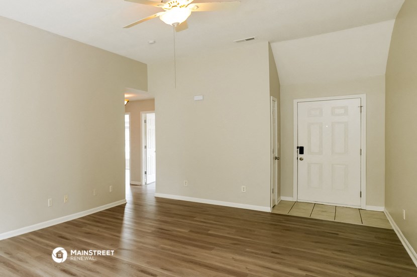 an empty living room with wood floors and a white door