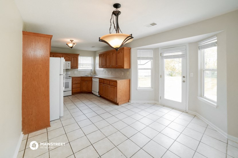 a kitchen with a white tiled floor and wooden cabinets