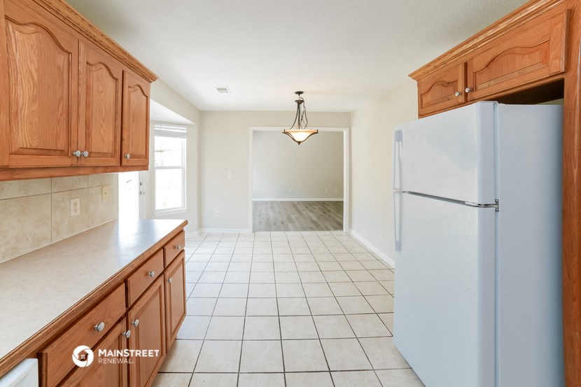 a kitchen with wooden cabinets and a white tiled floor and a refrigerator