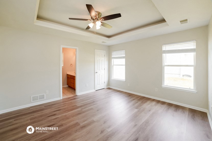 the spacious living room with hardwood flooring and a ceiling fan