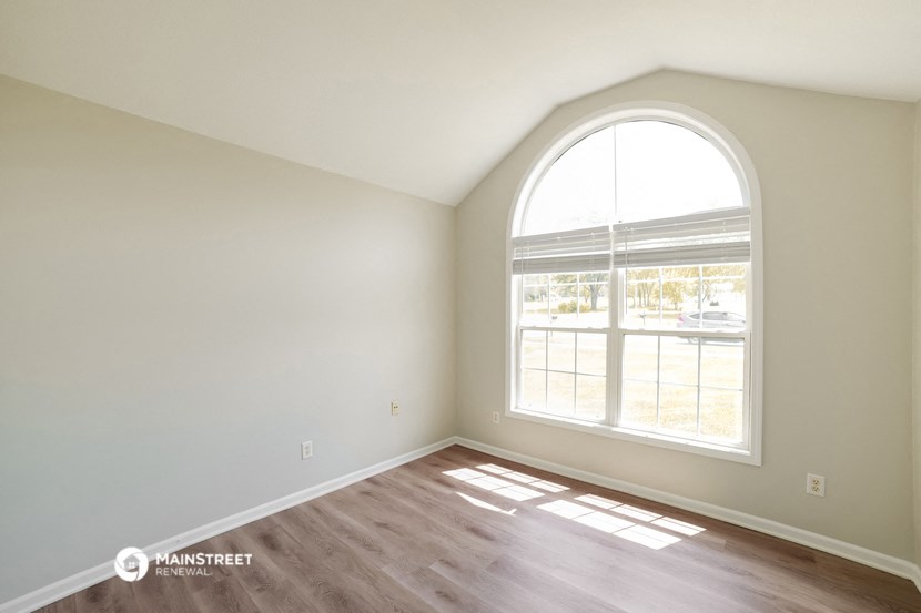 an empty room with a large window and wooden floors