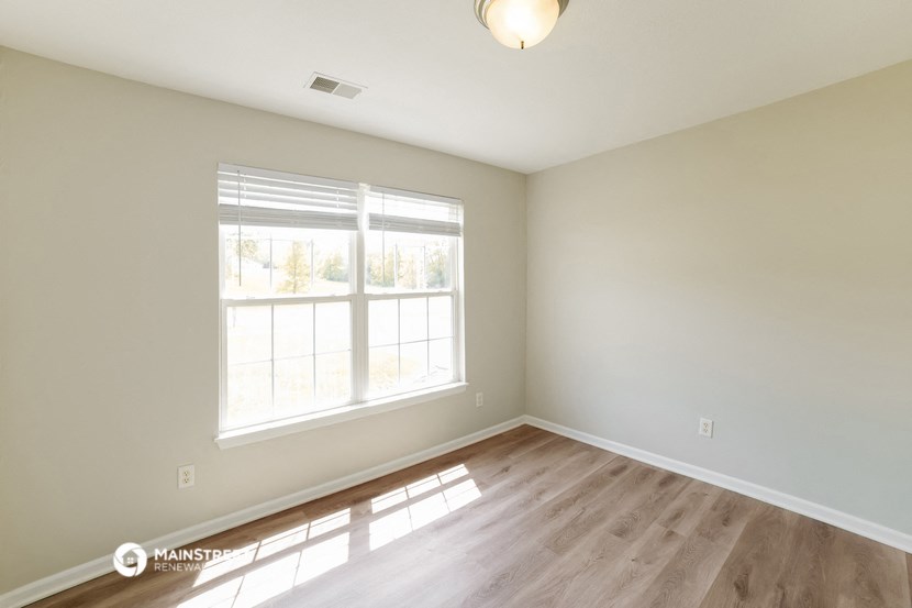 the spacious living room with hardwood flooring and a large window