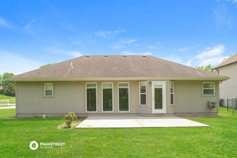 the backyard of a house with a lawn and a patio